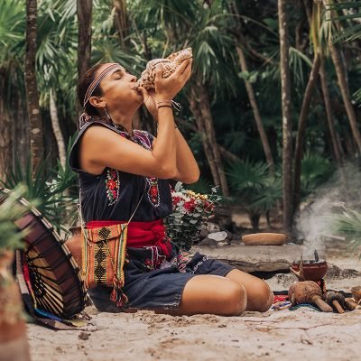 Native,Woman,In,Traditional,Clothes,Playing,Music,With,White,Shell Native,Woman,In,Traditional,Clothes,Playing,Music,With,White,Shell